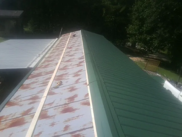 Old rusted panels beside newly installed green metal roofing — Wind Damage Roof Repair by Roofing Brothers in Beech Grove