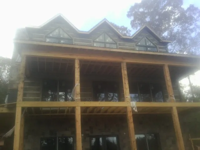 Dormers and porch framing on a large log home under construction — Roof Coating work by our crew in Beech Grove