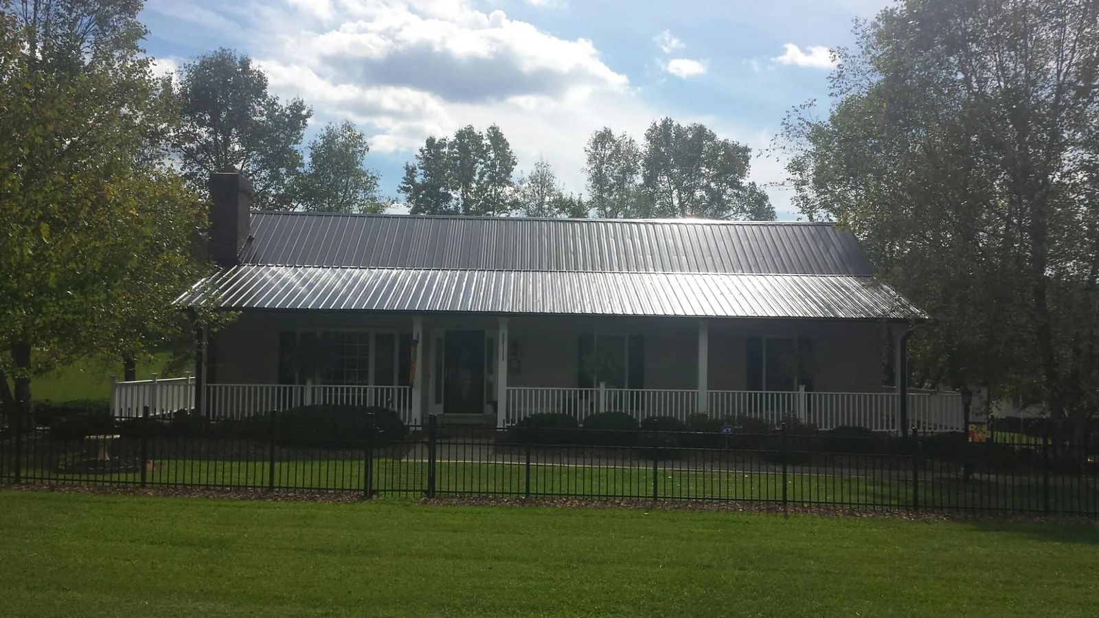 Gray metal roof on a brick ranch with a full width front porch — Gutter Guard Installation work by our crew in Beech Grove