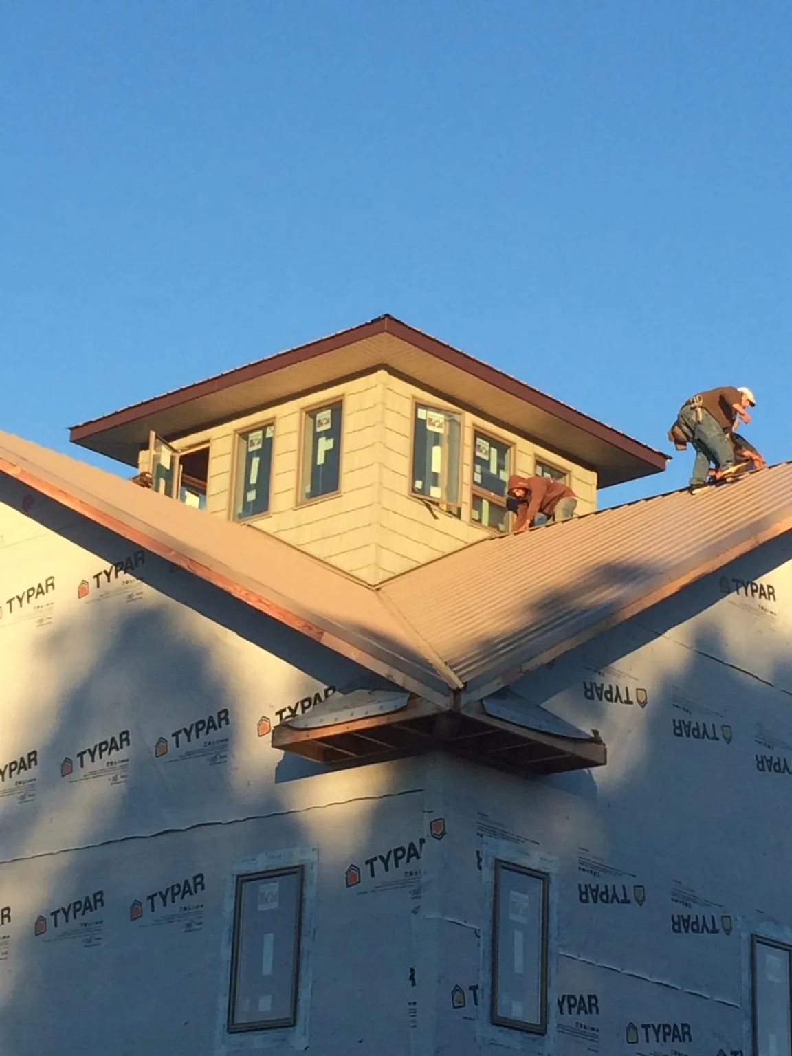 Roofers working around a rooftop cupola on a new metal roof at sunset — Roof Waterproofing in Beech Grove by Roofing Brothers